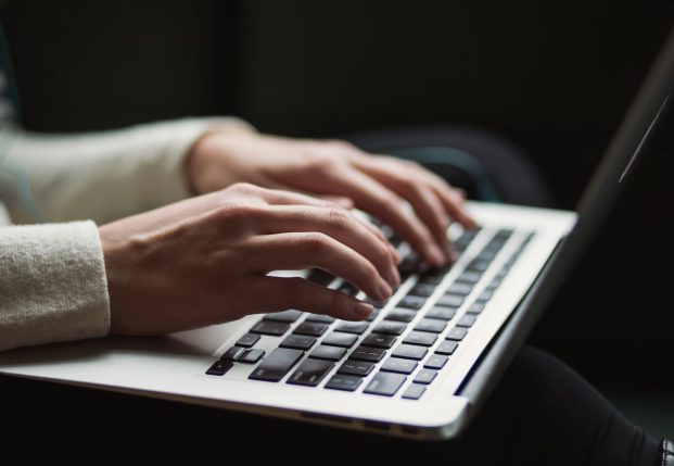Close up of woman's hands typing on a laptop keyboard while sitting down. Close up of woman's hands typing on a laptop keyboard while sitting down.