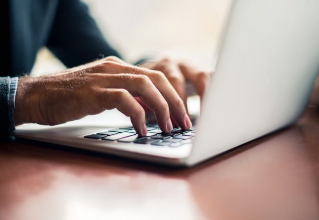Close up of mans hands typing on a laptop keyboard. Close up of mans hands typing on a laptop keyboard.