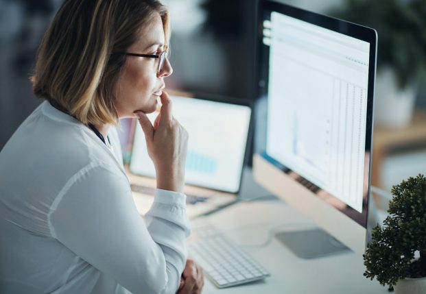 Woman with buttoned up white shirt looking at computer screen with a spreadsheet open. Woman with buttoned up white shirt looking at computer screen with a spreadsheet open.