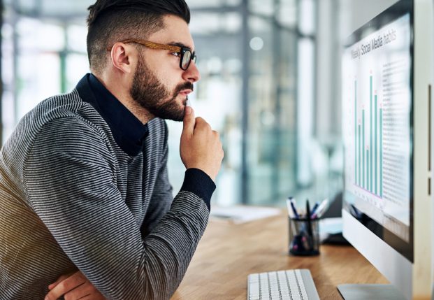Business worker review charts on a screen while sitting at desk in the office. Business worker review charts on a screen while sitting at desk in the office.