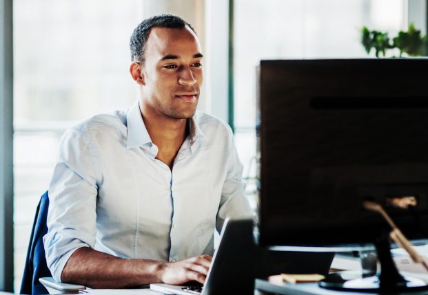 Business person in office looking at computer screen typing out information. Business person in office looking at computer screen typing out information.