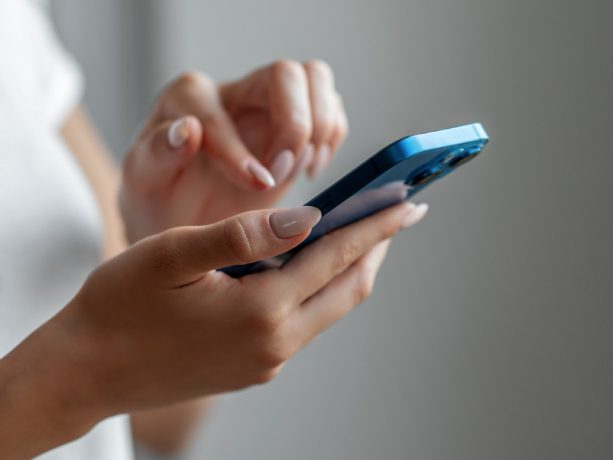 Hands holding an iPhone getting ready to touch the screen Hands holding an iPhone getting ready to touch the screen