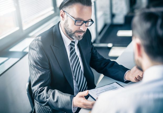 Business man in suit working with client reviewing documents together. Business man in suit working with client reviewing documents together.
