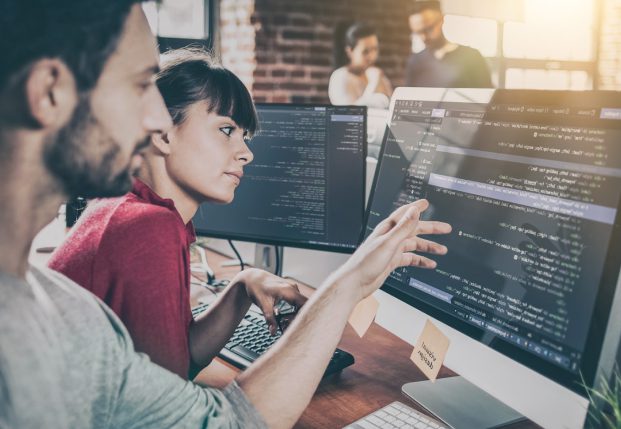 A man and woman collaborate on writing code on a computer screen A man and woman collaborate on writing code on a computer screen